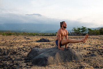 Man Practicing Yoga Meditation Outdoors in Nature with Mountain View.