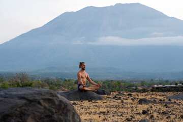 Man Practicing Yoga Meditation Outdoors in Nature with Mountain View.