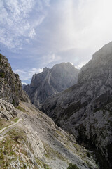 The mountain range is covered in snow and the sky is cloudy. The mountains are tall and majestic, and the clouds add a sense of depth and mystery to the scene