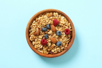 Delicious granola with berries on a color background