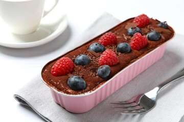 Delicious tiramisu cake with berries on table