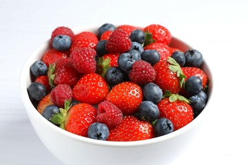 Different fresh ripe berries in bowl on the table