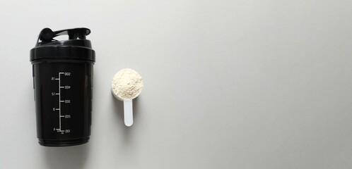 Whey protein powder with shaker for mixing on gray background