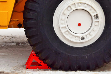 The wheel of a large dump truck is blocked by a wheel chock