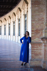 Naklejka premium moroccan woman brunette, young and beautiful, dressed in blue abaya, typical clothes of arab woman. The woman is in the square of Spain in Seville under the arches and columns. Travel concept.