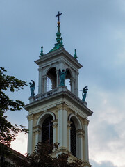 Ornate Church Tower with Angel Statues and Spire Against a Cloudy Sky