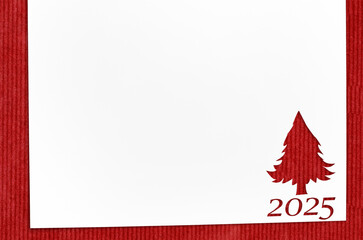 Christmas 2025 background. White paper with fir-tree shape cut for new year 2025 card on wooden table