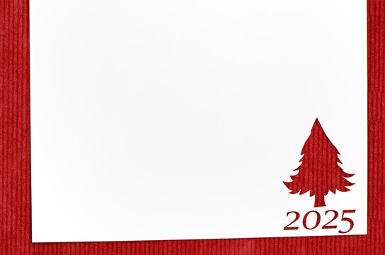 Christmas 2025 background. White paper with fir-tree shape cut for new year 2025 card on wooden table