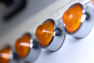 Close-up of a orange signal lamps in a row on a power distributor of a heating system. Analog device, electrical equipment, control panel technology.