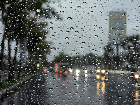 dew on car window on rainy day with blurred traffic view at night.
