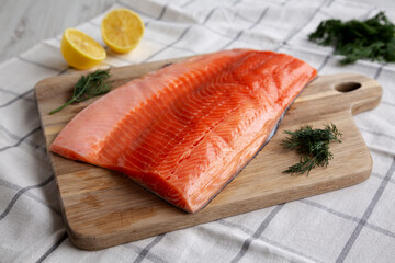 Organic Raw Salmon Fillet on a wooden board, side view.