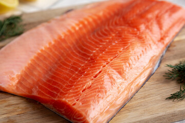 Organic Raw Salmon Fillet on a wooden board, side view.