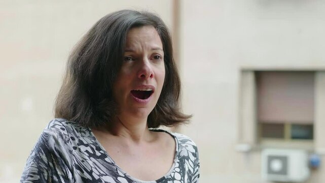 A young brunette woman sitting and yawning out of boredom, looking casual and relaxed, capturing a relatable everyday moment.