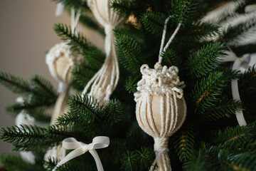 White knitted toy on the branches of a christmas tree.