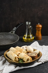 Delicious vegetarian crepes with mushrooms served on a wooden plate with cooking essentials nearby