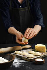 Hands preparing dough for homemade pasta with cheese and flour on the kitchen table