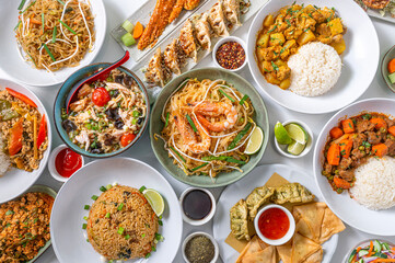 Set of Thai dishes top view on white background. Composition of traditional Asian food with noodles, pad thai, ramen, chicken massaman, beef panang, stuffed dumplings.