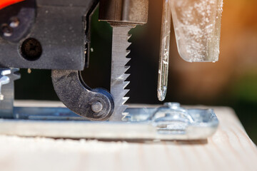 The builder works with a jigsaw. The craftsman cuts the board with a jigsaw.