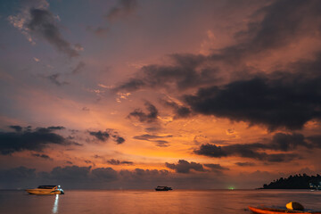 Sky with clouds above tropical beach at colorful sunset