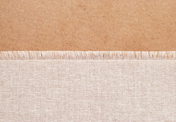 A piece of cotton fabric with fringe on brown cardboard background as a banner