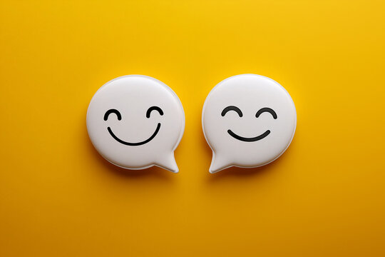 Two white speech bubbles with happy  face expressions on a yellow background, a flat lay composition, a minimalist concept of positive and negative emotions in online commun