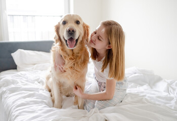 Girl Poses With Golden Retriever In Bed In The Morning In A Bright Room