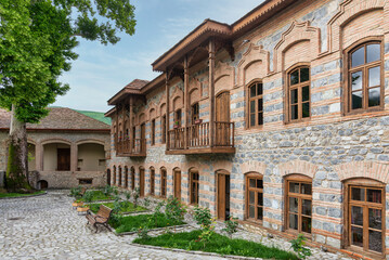 Exterior view of Shaki Khan Mosque Complex, a historic structure located in Shaki, Azerbaijan. The complex is characterized by stone walls, wooden balconies, and traditional architectural elements