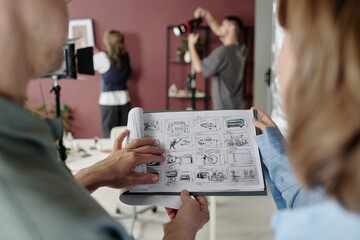 High angle shot of unrecognizable man and woman looking at black and white sketches on paper while...