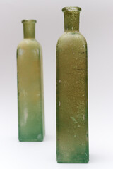 two vintage green glass bottles with a textured, weathered finish