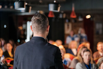 Presenter giving a speech to an attentive audience in a professional business event.