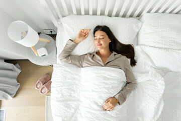 Top view of calm lady sleeping well on her back, resting, enjoying fresh cotton bedding, soft...