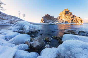 Beautiful landscape of Lake Baikal on a frosty December morning. The famous Shamanka Rock in the light of the rising sun - a natural landmark of Olkhon Island and a place of attraction for tourists