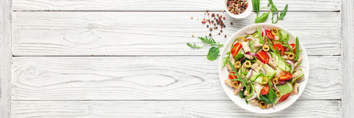 Fresh salad with vegetables and fish. Arugula, spinach, cucumbers, tomato, onions and fish in a plate on the table. Diet nutrition. Top view. Copy space