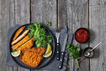 Pork Milanese with lettuce and lemon on a plate