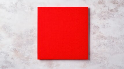 Fototapeta premium A vibrant red book rests on a textured white surface