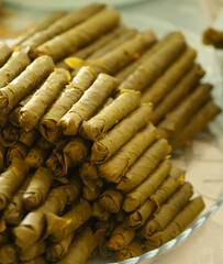 Homemade stuffed vine leaves are arranged in a row on the table,
