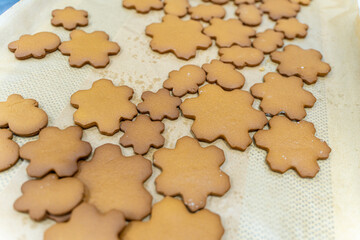 Snowflake-shaped cookies are ready to be decorated with frosting on baking paper. The process of cooking a New Year's or Christmas treat, recipe.