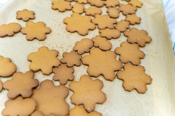 Snowflake-shaped cookies are ready to be decorated with frosting on baking paper. The process of cooking a New Year's or Christmas treat, recipe.
