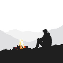 Silhouette of a man sitting by a campfire in the mountains.