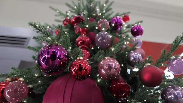 Low angle closeup footage of the shiny, reflective colorful ornaments on a Christmas tree