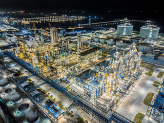 Fototapeta premium Oil refinery chemical plant industrial equipment at night in large industrial area. Business finance and industry