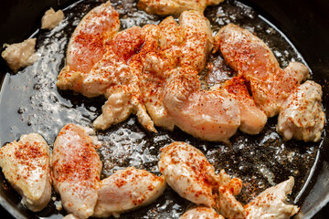 chicken fillet fried in spices and oil crispy crust in a frying pan