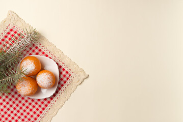 Christmas tree branch with oranges dusted with snow on beige background. Flat lay, top view. Copy space