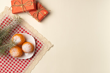 Christmas tree branch with oranges dusted with snow and gift boxes on beige background. Flat lay, top view. Copy space