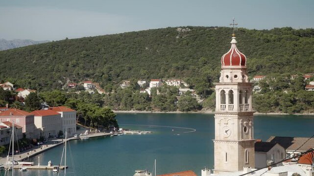 The ancient building of the parish church of Saint Jerome of Stridon in the port town of Pucisca (Puči&scaron;ća) on the island of Brac (Brač), Croatia. A bell tower with a clock on a stone church tower.