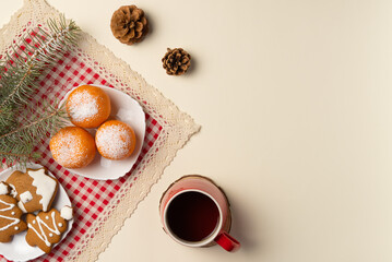 Christmas tree branch with oranges dusted with snow, gingerbread and cup of tea on beige background. Flat lay, top view. Copy space