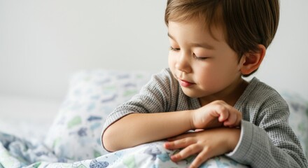 Fototapeta premium Young asian child resting in bed with patterned blanket