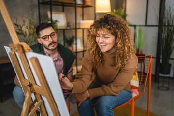 Adult caucasian couple paint on canvas easel at home together