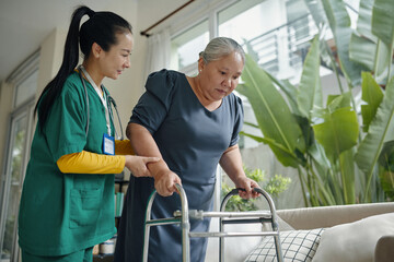 Senior woman walking with the help of nurse and walker