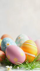 Naklejka premium Easter Eggs in Spring Grass: Decorated Easter eggs nestled in green grass with small white flowers, a festive springtime scene